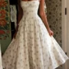 Claudia – cremefarbenes Midi-Kleid aus Stretch-Baumwolle mit Gänseblümchenprint und Neckholder-Ausschnitt Claudia – cremefarbenes Midi-Kleid aus Stretch-Baumwolle mit Gänseblümchenprint und Neckholder-Ausschnitt