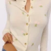 Poppie Cremefarbene Strickjacke aus Wolle und Kaschmir mit rosa Blumenstickerei Poppie Cremefarbene Strickjacke aus Wolle und Kaschmir mit rosa Blumenstickerei