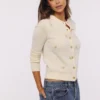 Poppie Cremefarbene Strickjacke aus Wolle und Kaschmir mit rosa Blumenstickerei Poppie Cremefarbene Strickjacke aus Wolle und Kaschmir mit rosa Blumenstickerei